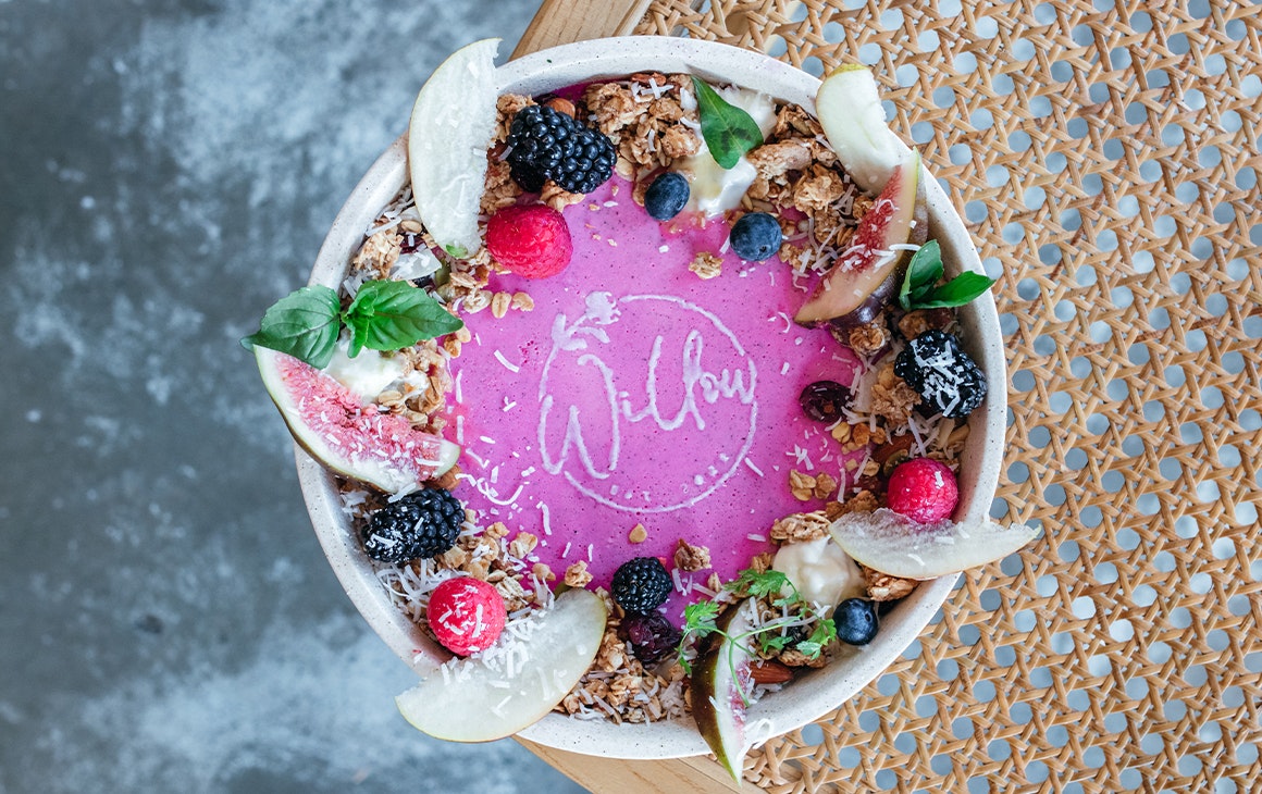 a bowl of pink panna cotta with fruit and granola seen from the top down